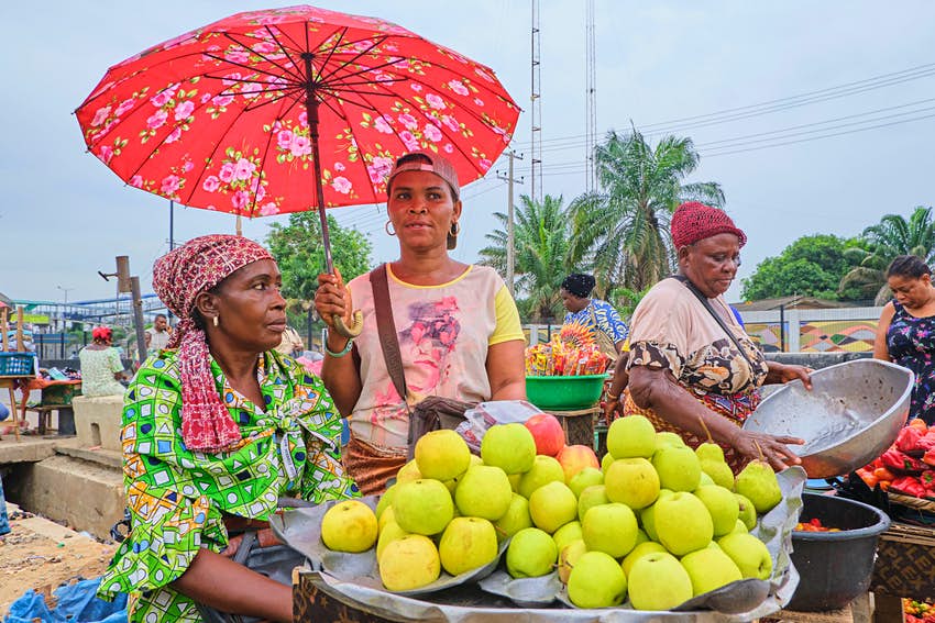 Comerciantes que venden manzanas y verduras en un mercado de Lagos, Nigeria.